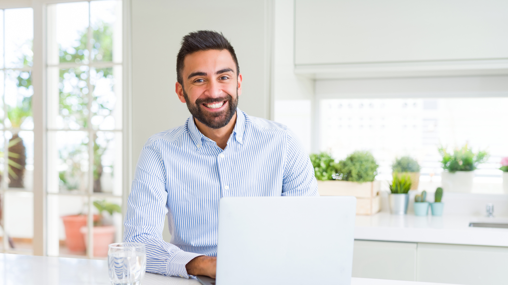 smiling man sitting behind laptop